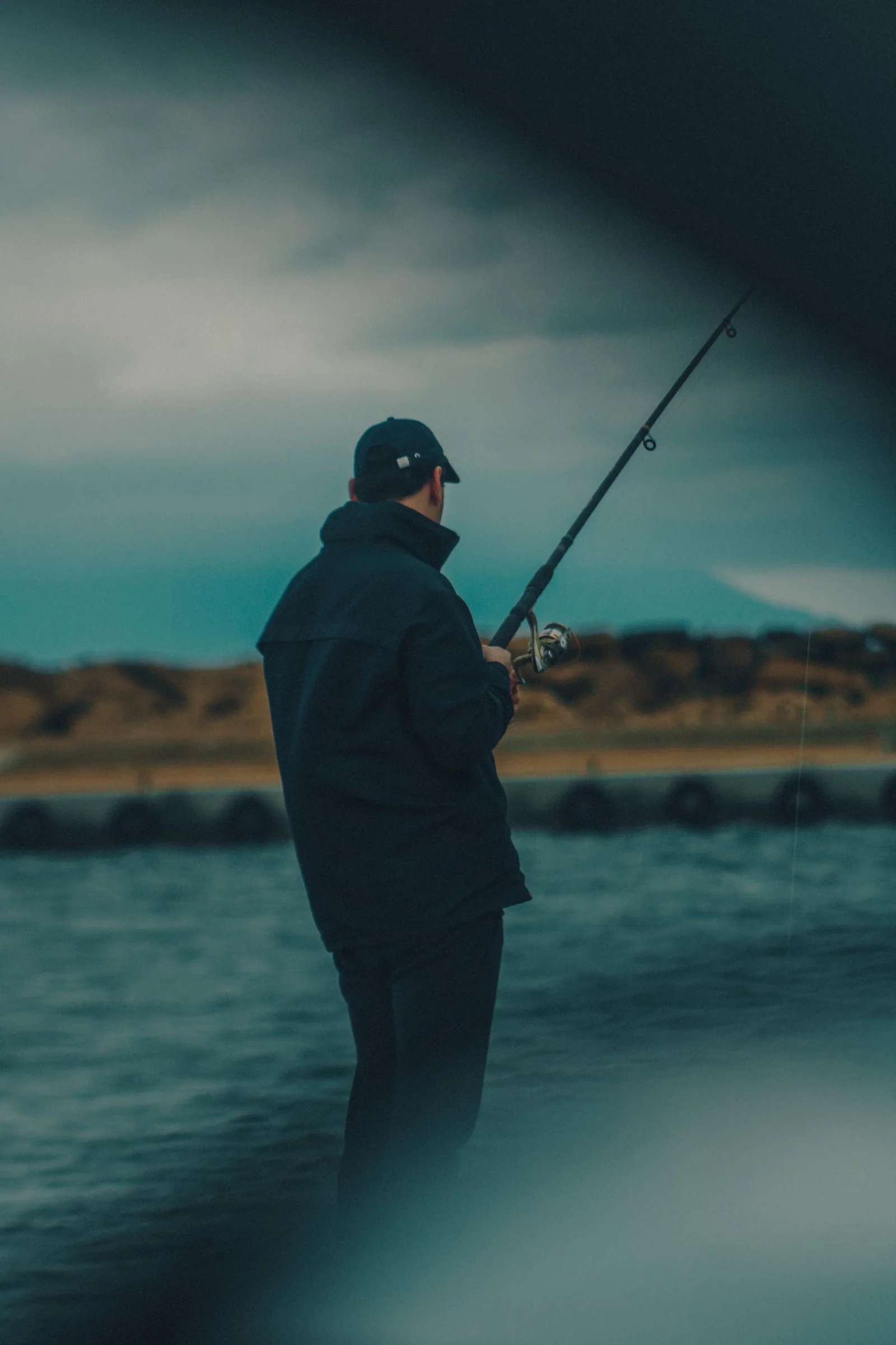 Angler holding a rod under a moody sky